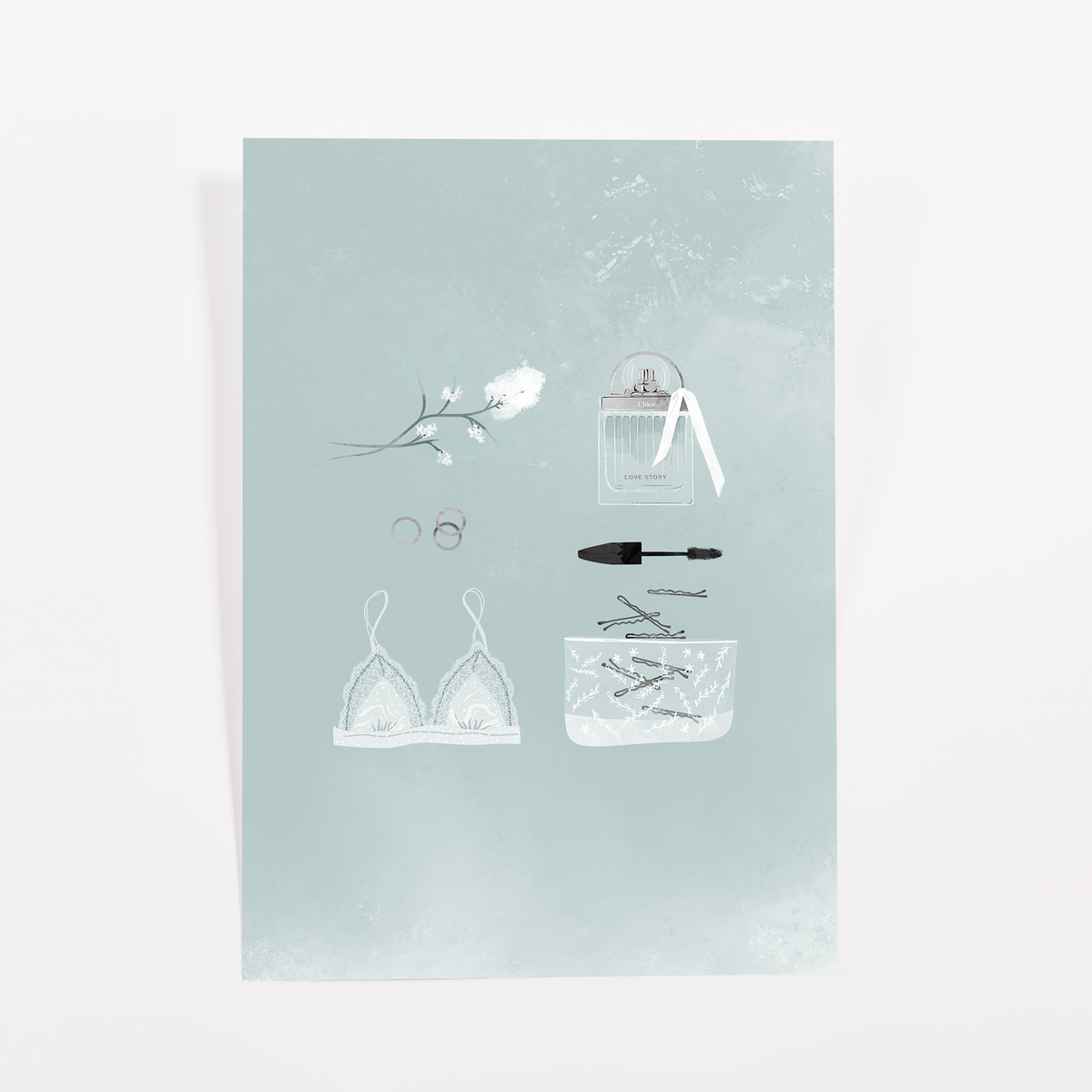 Teal journaling card with a white lace bralette, a perfume bottle with ribbon, mascara, rings, and a white blossom sprig