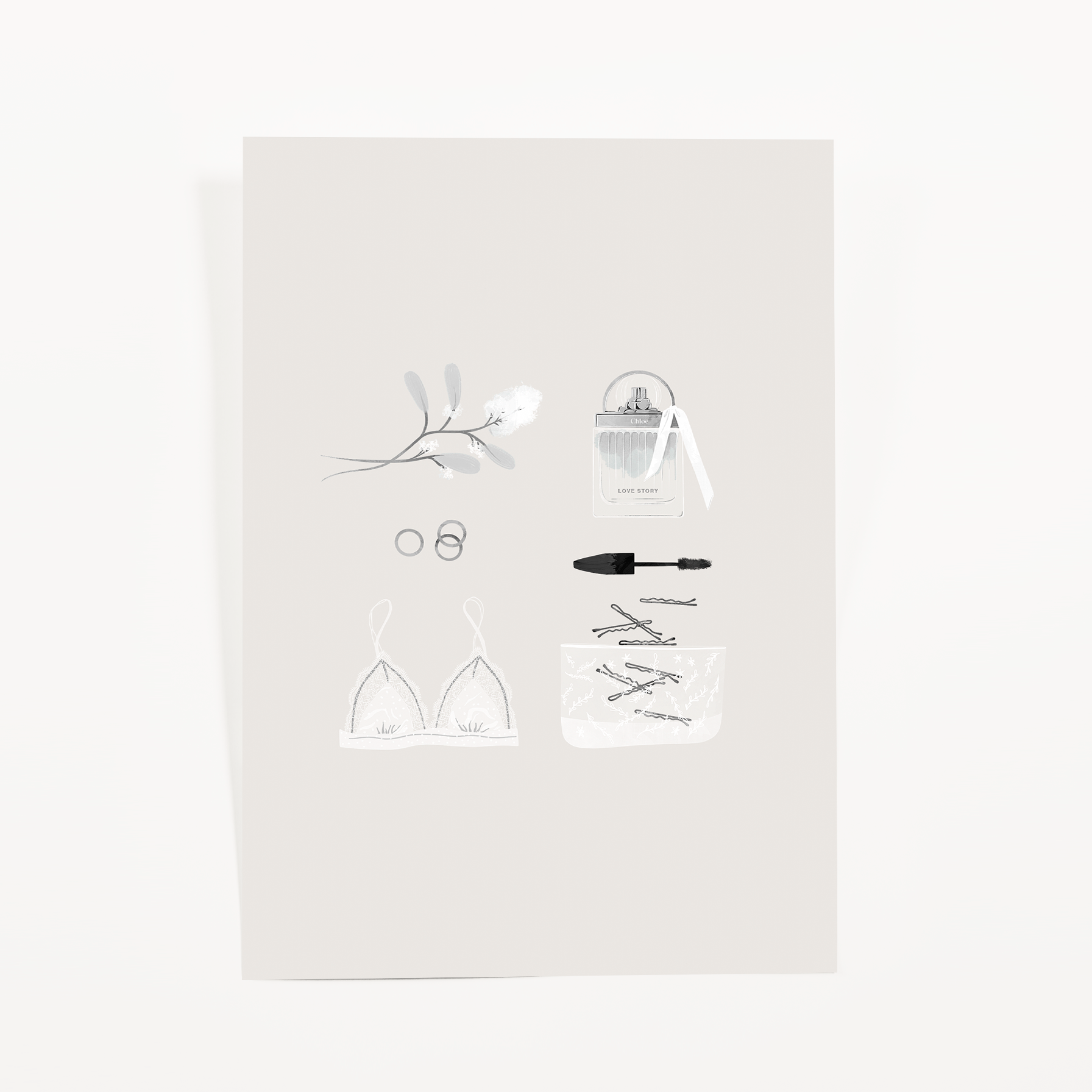 Soft gray journaling card with a white lace bralette, a perfume bottle with ribbon, mascara, rings, and a blossom sprig