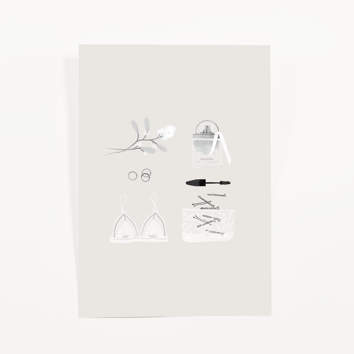 Soft gray journaling card with a white lace bralette, a perfume bottle with ribbon, mascara, rings, and a blossom sprig