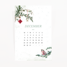 December 2025 calendar card with a snowy pine branch, a house charm and a bullfinch on snow